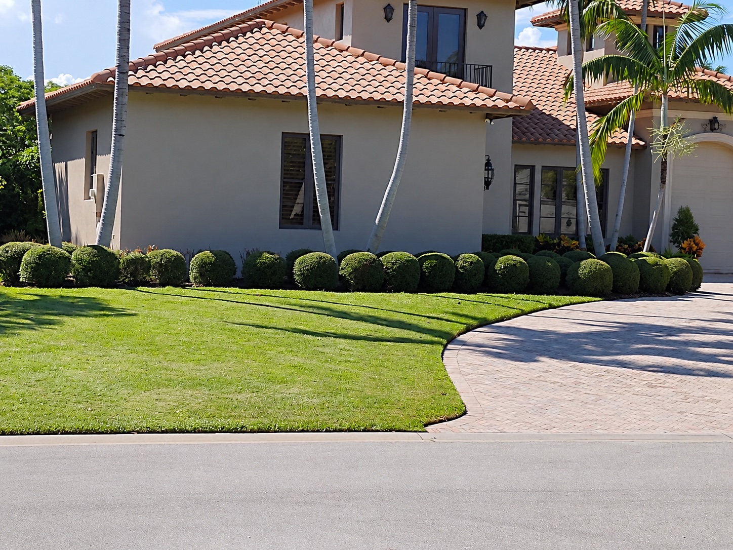 Evenly cut lawn with crisp curved edges and a row of neatly shaped shrubs beside a South Florida home